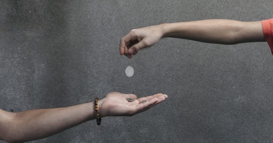Hand lässt Münzen in andere Hand fallen. Geldspende. FR