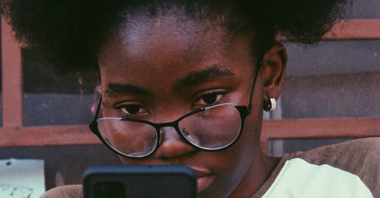 Eine junge Frau schaut auf ihr Smartphone.