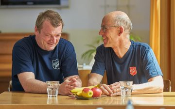 Dirk sitzt zusammen mit Rolf Girschweiler, dem Institutionsleiter des Wohnheims Winterthurs, an einem Tisch.