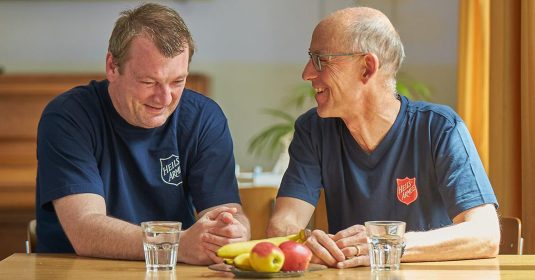 Dirk sitzt zusammen mit Rolf Girschweiler, dem Institutionsleiter des Wohnheims Winterthurs, an einem Tisch.