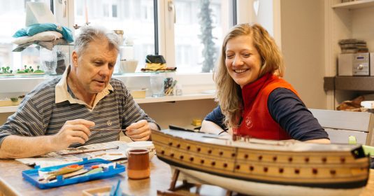 Ein Mann und eine Frau begutachten ein selbst hergestelltes 3D-Puzzle eines Schiffes.