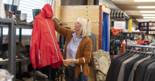 Frau begutachtet Windjacke in Brocki Laden