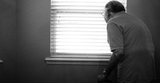 Einsamer alter Mann schaut durchs Fenster.