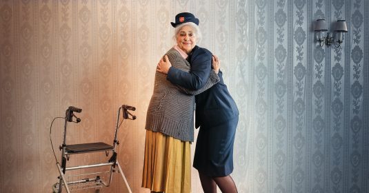 Kampagnenbild: Eine Heilsarmee-Offizierin umarmt einen ältere Dame.