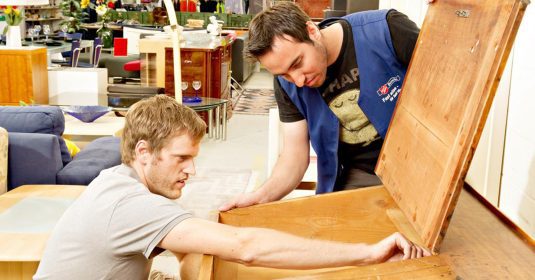 Zwei Männer präparieren eine Kiste für den Brocki.ch Verkauf.