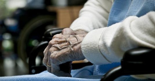 Hände einer älteren Frau im Rollstuhl