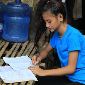 Elyn aus den Philippinen macht Hausaufgaben. Dank der Heilsarmee kann sie wieder zur Schule.