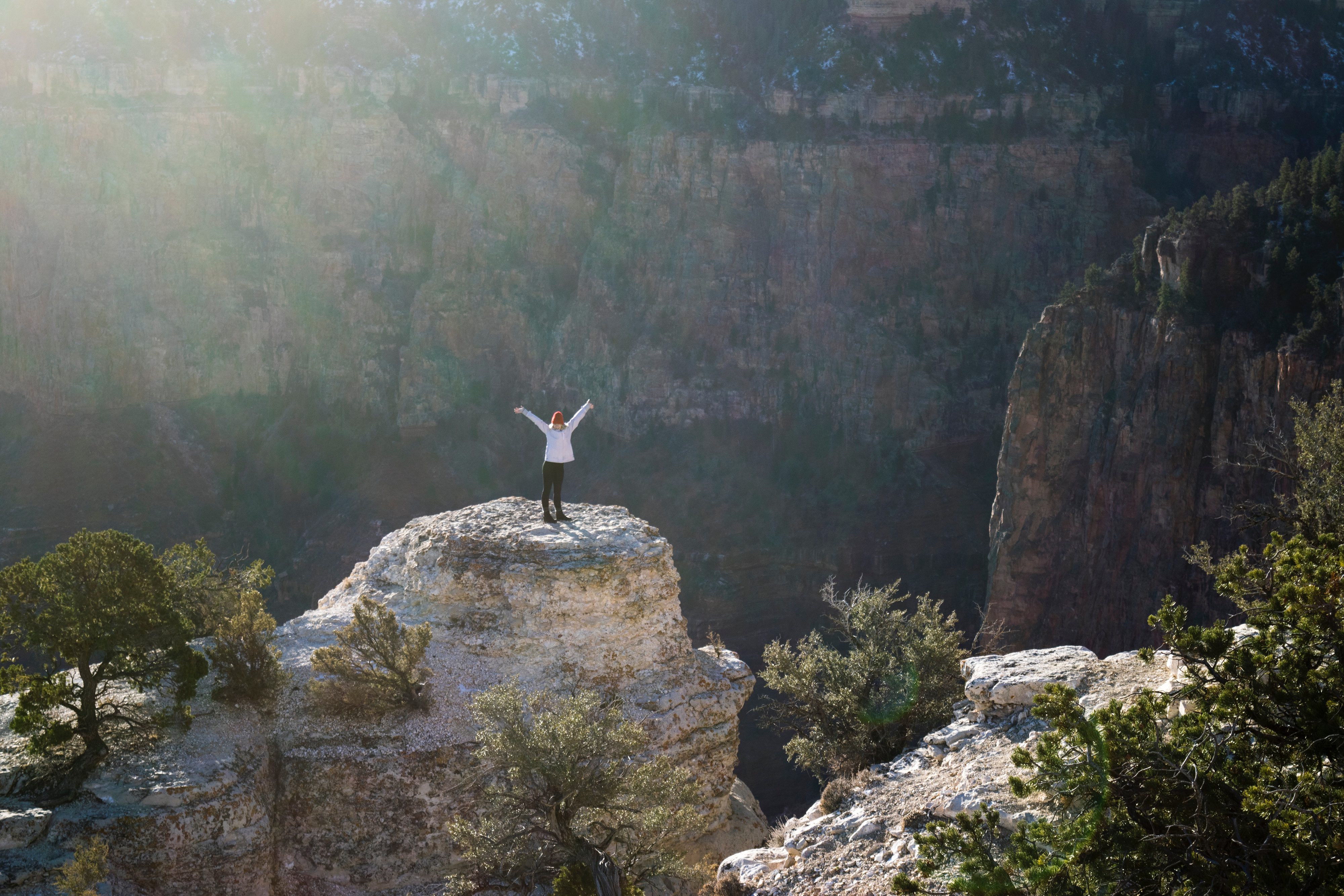 Frau mit Händen in der Luft auf einem Felsvorsprung