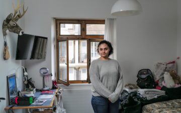 Eine Junge Frau steht in einem unaufgeräumten Zimmer